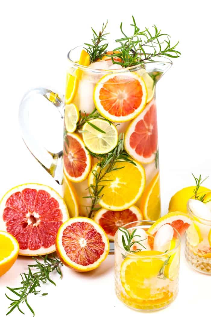 a pitcher filled with lemons, grapefruit and rosemary