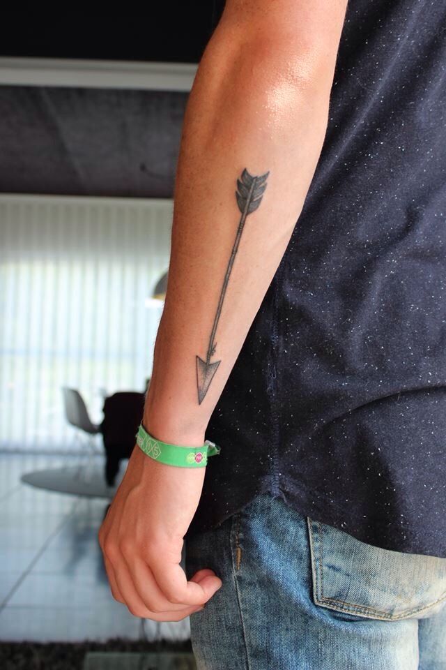 a man with a green bracelet and an arrow tattoo on his arm