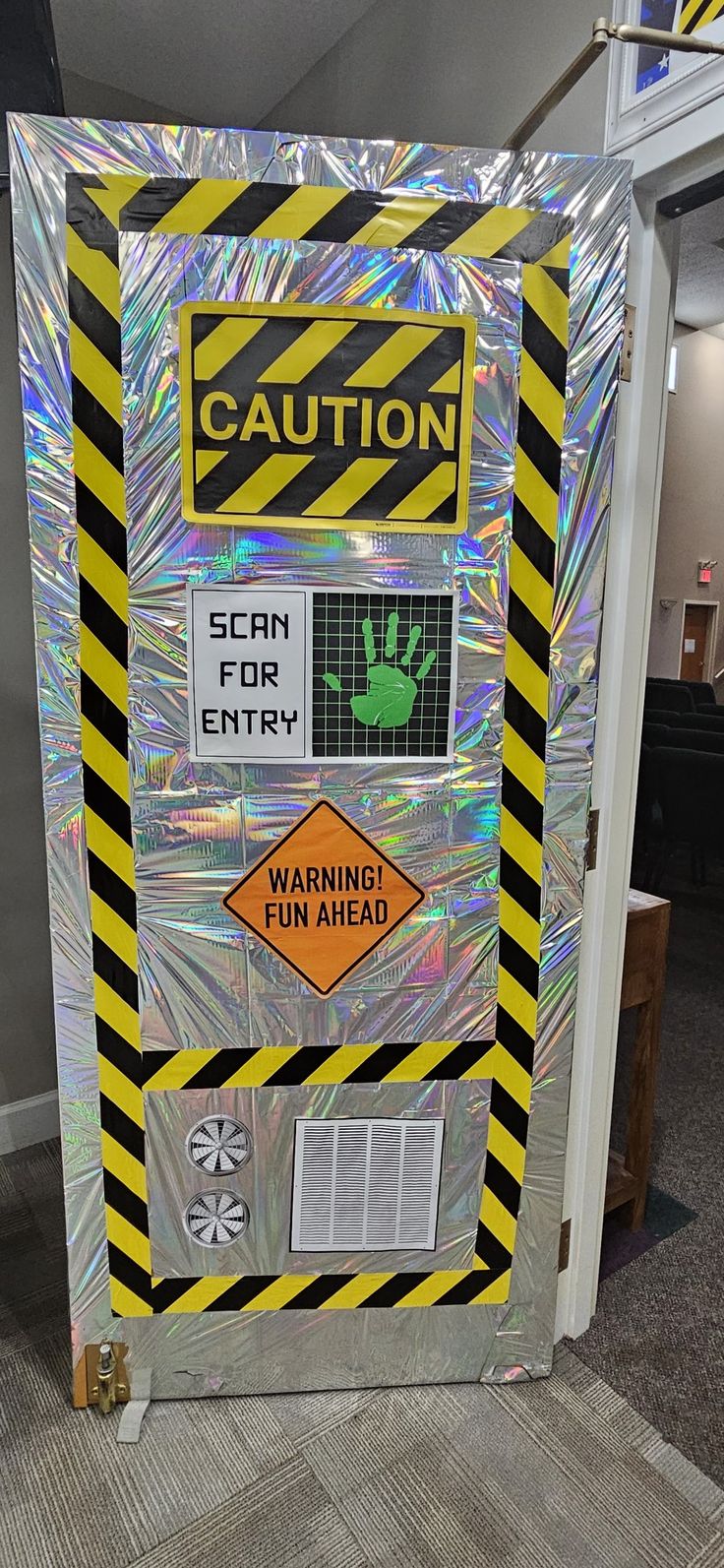 a caution sign is on display in an office cubicle with reflective foil covering it