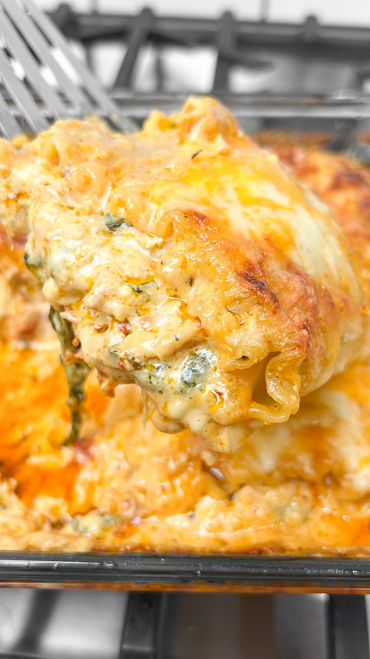 a casserole dish with cheese and spinach being lifted from an oven rack