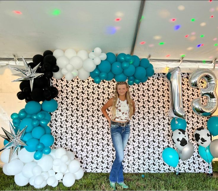 a woman standing in front of a backdrop with balloons