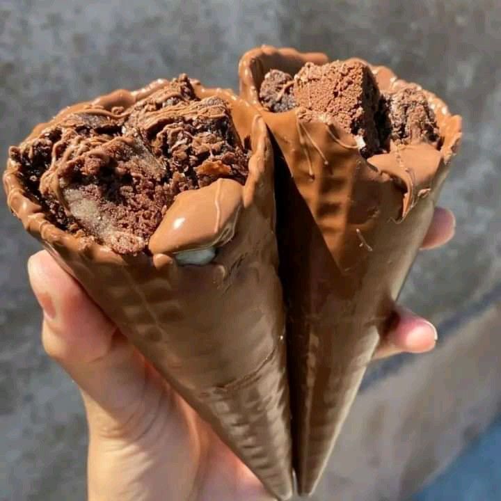 two ice cream cones with chocolate fillings in their wrappers, held up to the camera