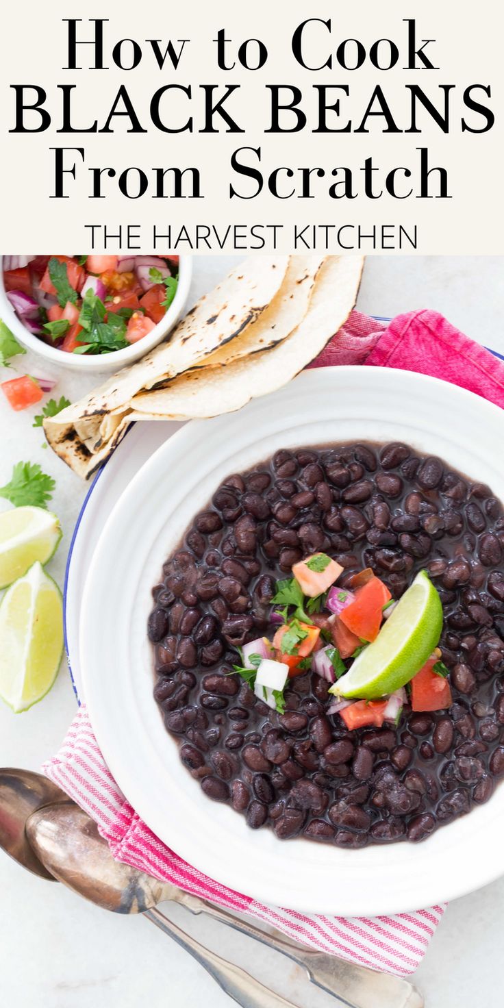 a white bowl filled with black beans next to tortillas