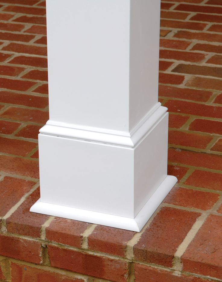 a white pillar on the side of a brick wall