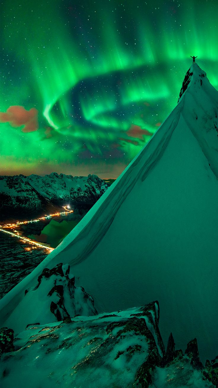 an aurora bore is seen above the snow covered mountains in this photo taken at night