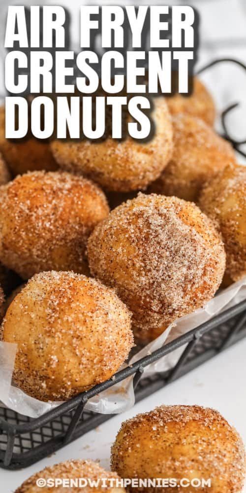 air fryer crescent doughnuts in a basket with powdered sugar on top