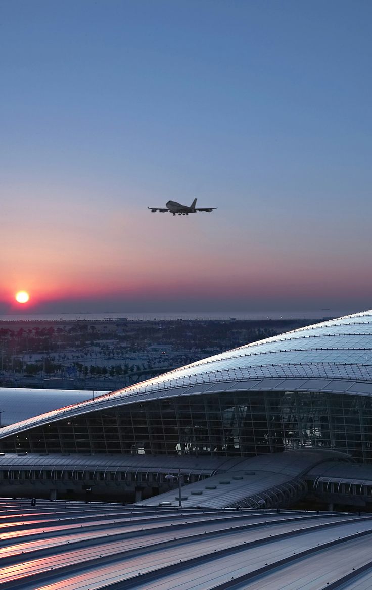 an airplane is flying over the airport at sunset