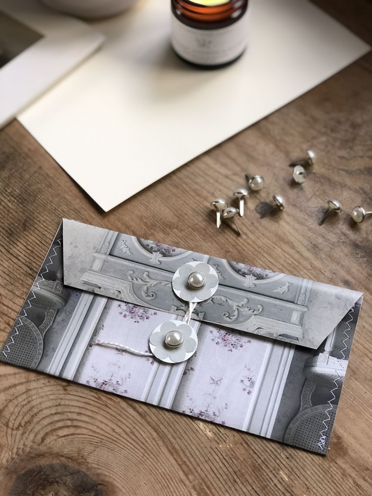 an open envelope sitting on top of a wooden table next to beads and a jar