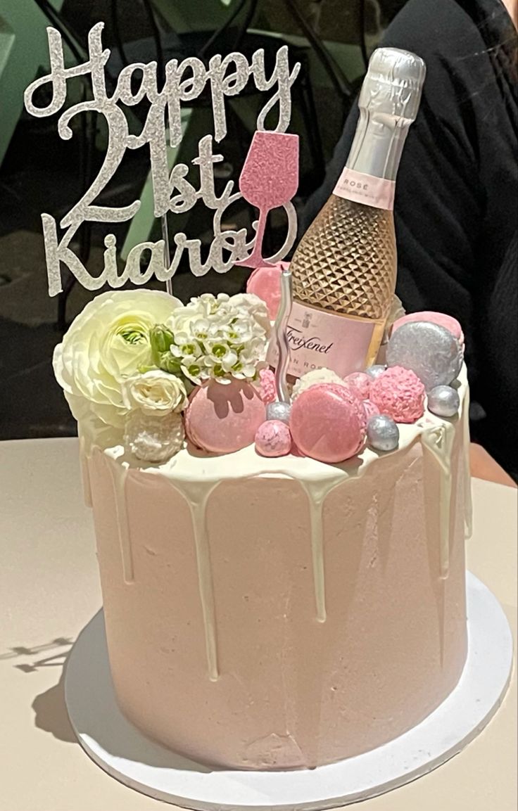 a birthday cake with pink frosting and decorations on top, sitting on a table