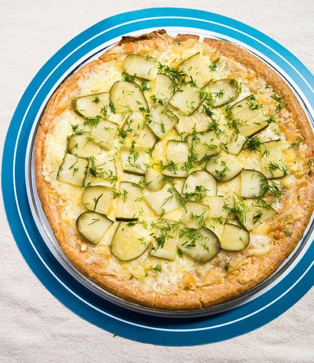 a pizza with cucumbers is on a blue and white plate