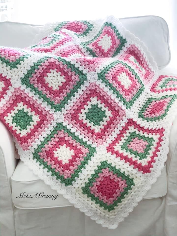 a crocheted blanket is sitting on a white couch in front of a window