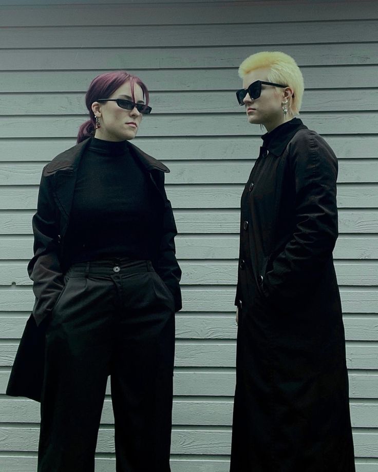 two people dressed in black standing next to each other