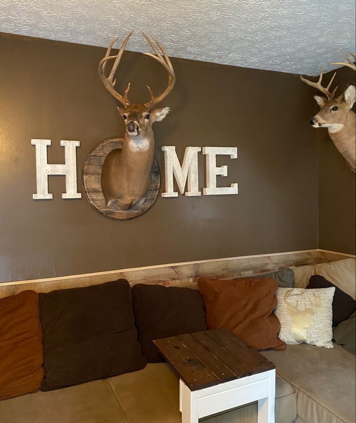 a living room with deer heads mounted on the wall and couches in front of it