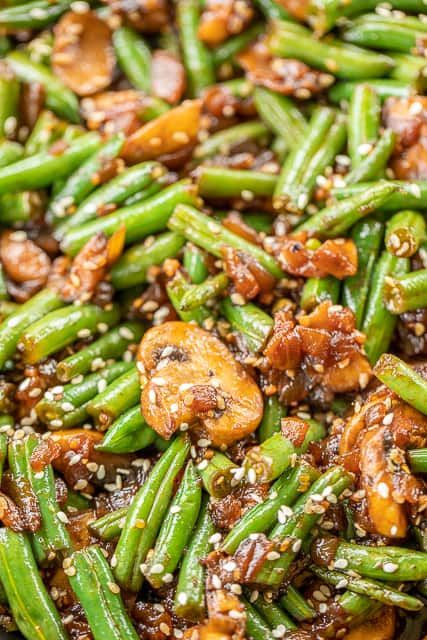 green beans and mushrooms with sesame seeds in a pan