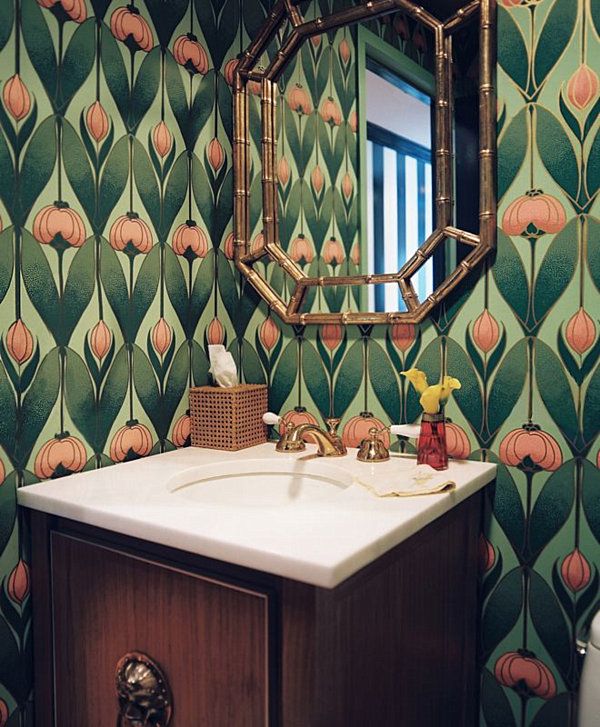 a bathroom with wallpaper and a gold faucet - shaped mirror in a powder room