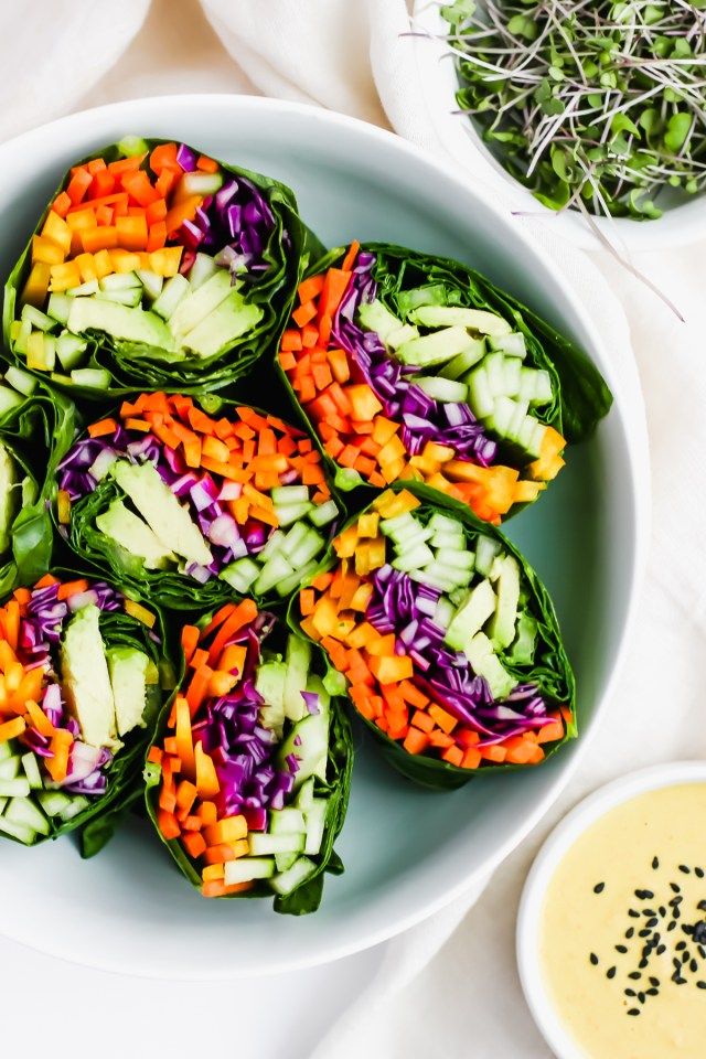 a white bowl filled with lettuce and veggies next to dipping sauce