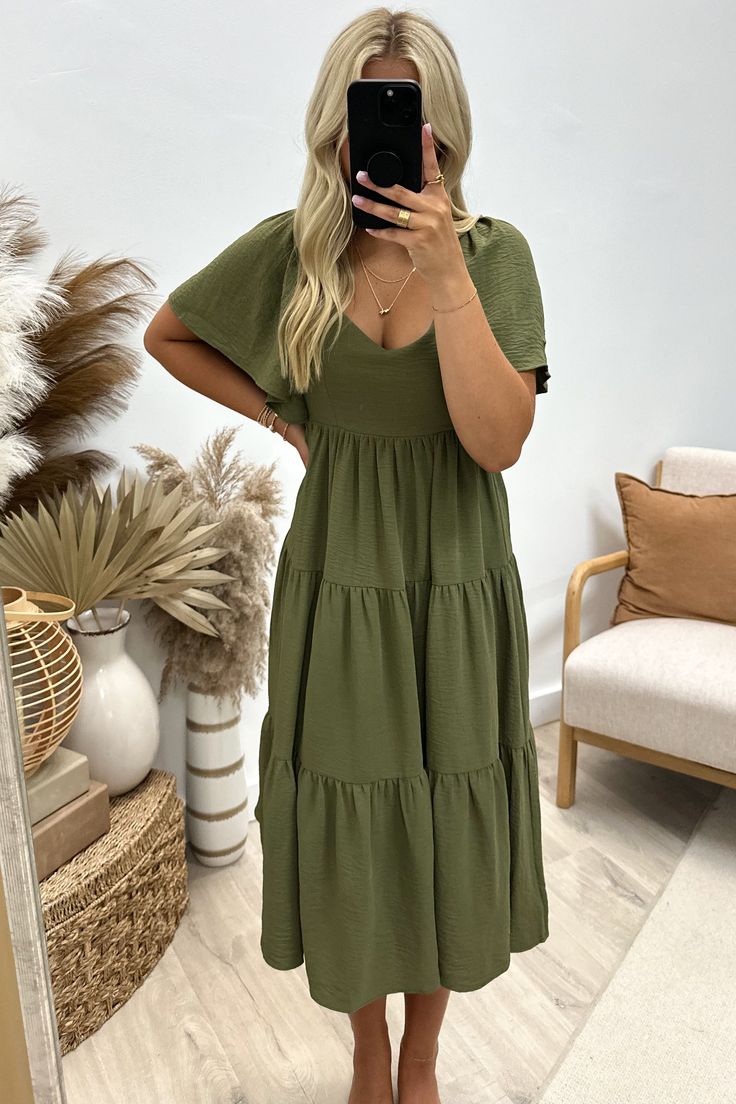 Flaunt your unique style in the "Enchanting You" Midi Dress. This playful olive green dress features flounce sleeves and a tiered design, complete with a back cross tie for added charm. Perfect for any occasion, this dress will have you feeling confident and enchanting. 100% Polyester Riley is a size 1, wearing a small. Forest Green Dress Outfit, Forest Green Dress, Green Dress Outfit, Forest Green Dresses, Olive Green Dress, Sky Collection, Olive Green Dresses, Feeling Confident, Flounce Sleeve