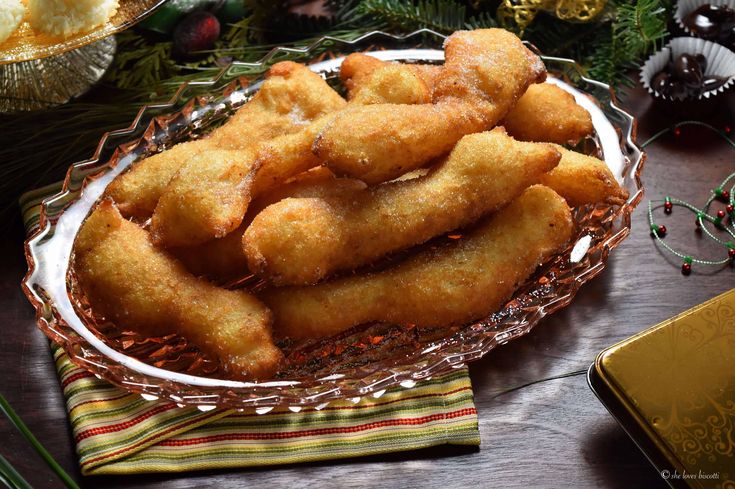 a glass dish filled with fried food on top of a table next to christmas decorations