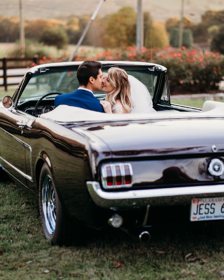 a bride and groom kissing in the back of a classic car