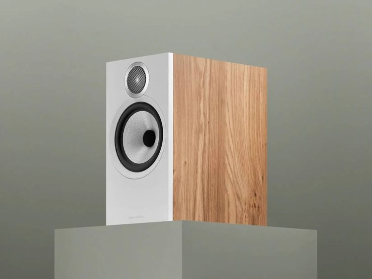 a speaker on top of a wooden block in front of a gray wall and floor