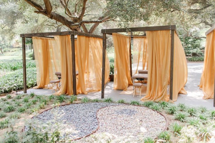 an outdoor area with yellow drapes and chairs