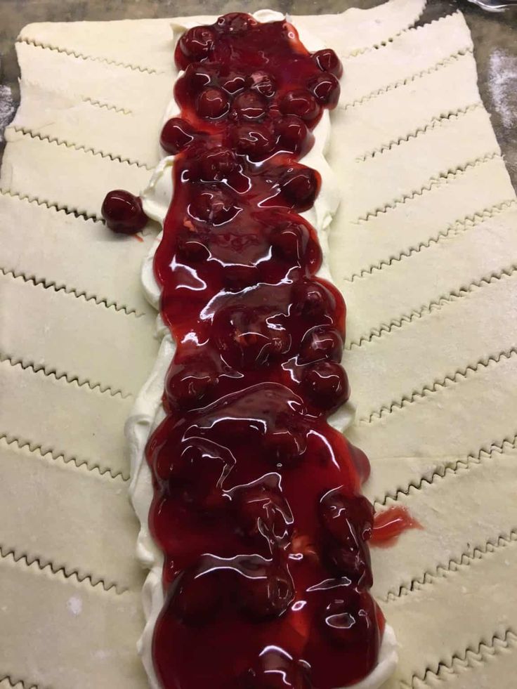 the long pastry is covered with cherries and icing