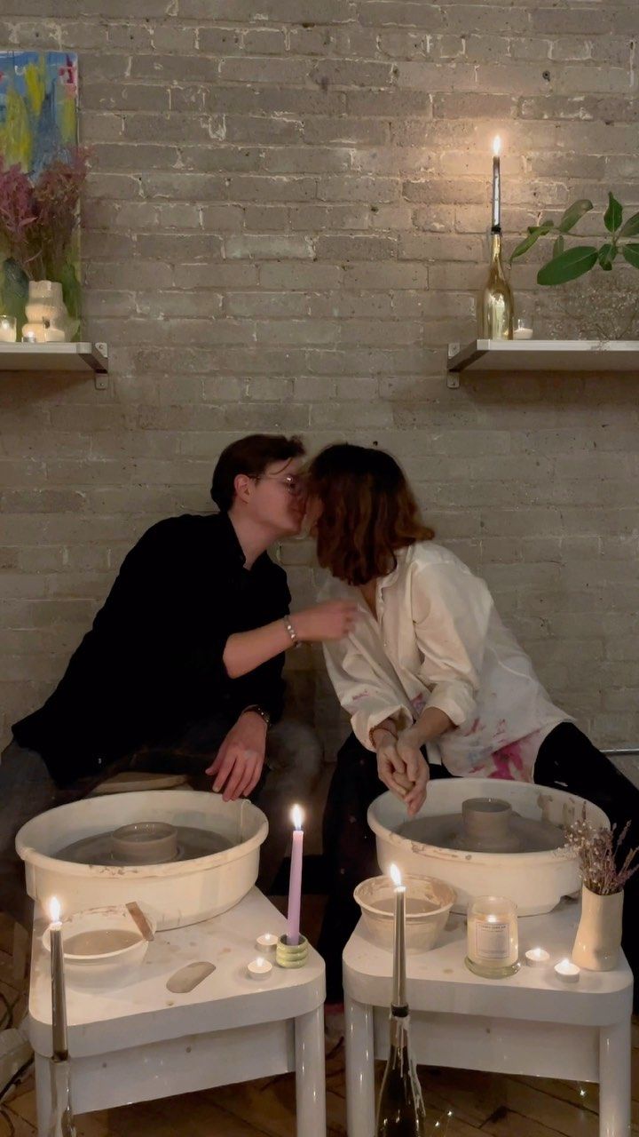 a man and woman kissing in front of candles