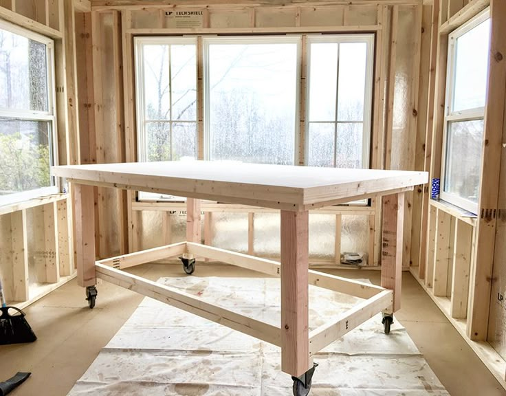 a table being built in the middle of a room with windows and tools on the floor