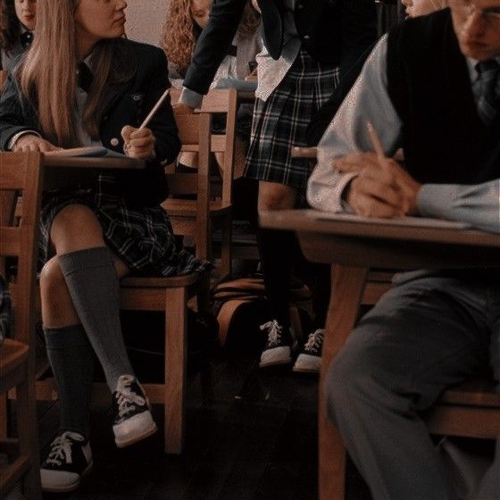 a group of people sitting at desks in a classroom with one person writing on a paper