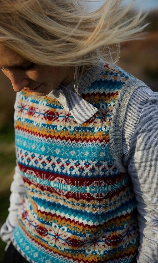 a woman with her hair in the wind wearing a knitted sweater over her shoulders