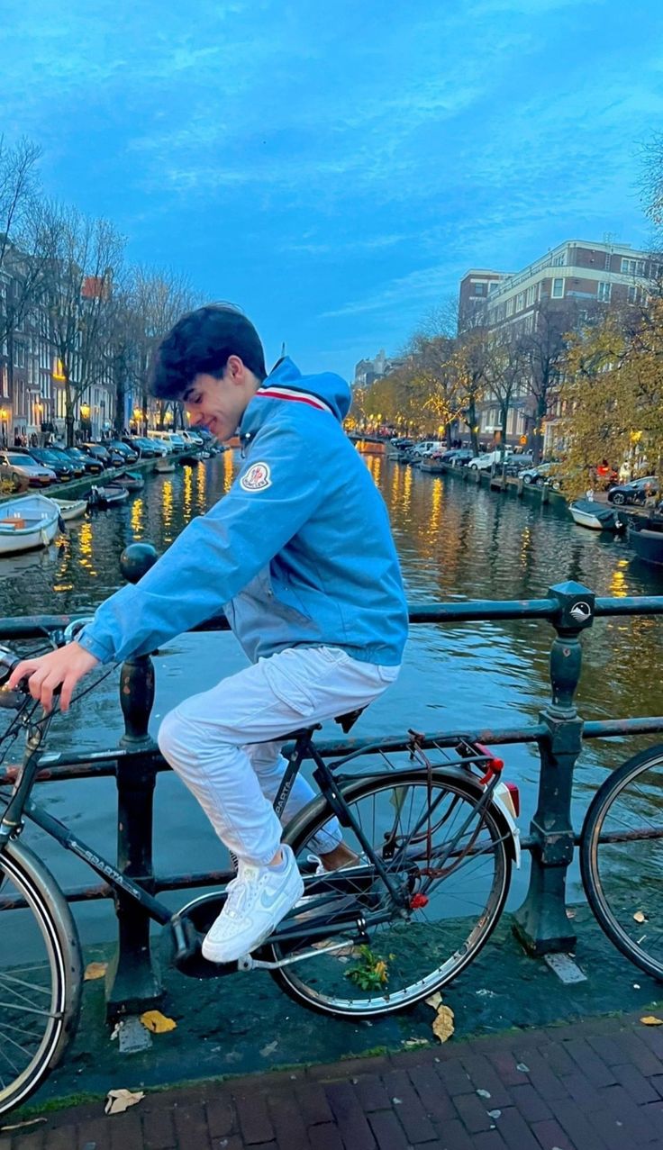 a man sitting on top of a bike next to a body of water