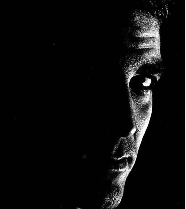 black and white photograph of a man's face in the dark