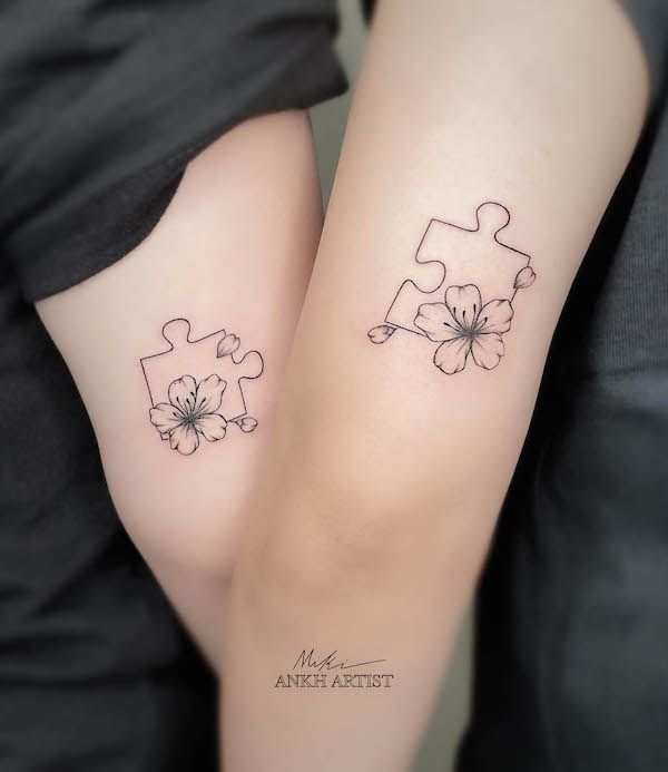 two people with matching tattoos on their legs, one has a puzzle piece and the other has a flower