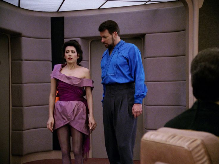 a man standing next to a woman in a dress on the set of star trek