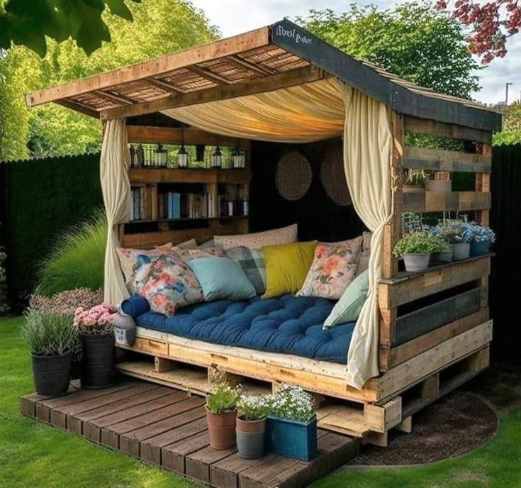 a bed made out of wooden pallets with blue cushions and pillows in the middle