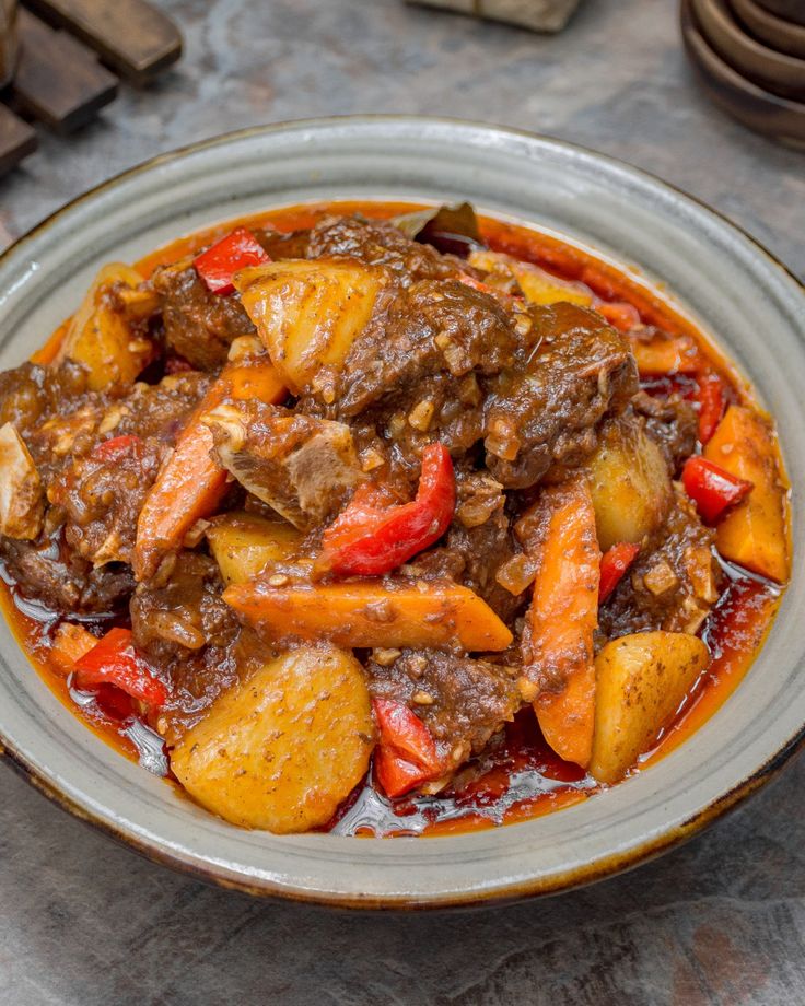 a bowl filled with stew and potatoes on top of a table next to other dishes