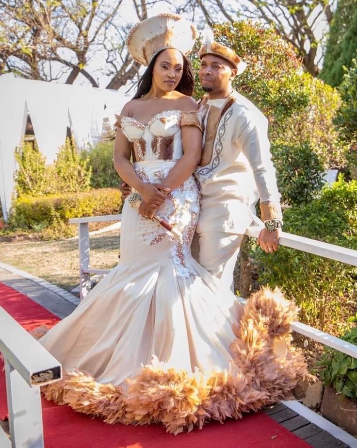 a man and woman standing on a red carpet next to each other in wedding dresses