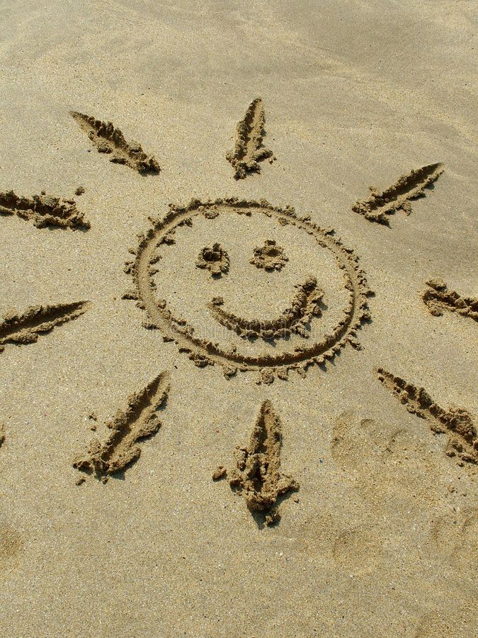 a smiley face drawn in the sand at the beach