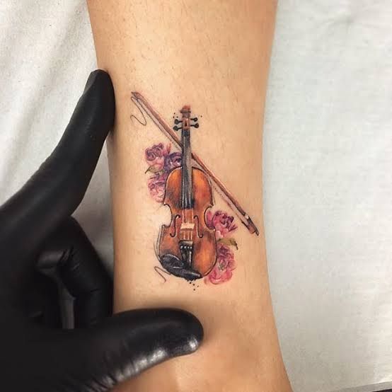 a person with a violin tattoo on their arm and hand next to a black glove