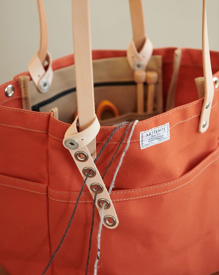 an orange tote bag with two wooden handles