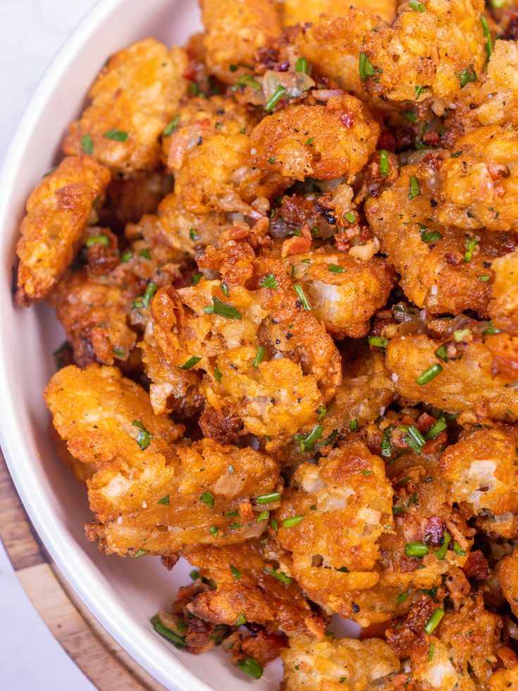 a white bowl filled with fried food on top of a wooden table