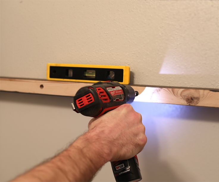 a man using a drill to fix a wall with a screwdriver on it