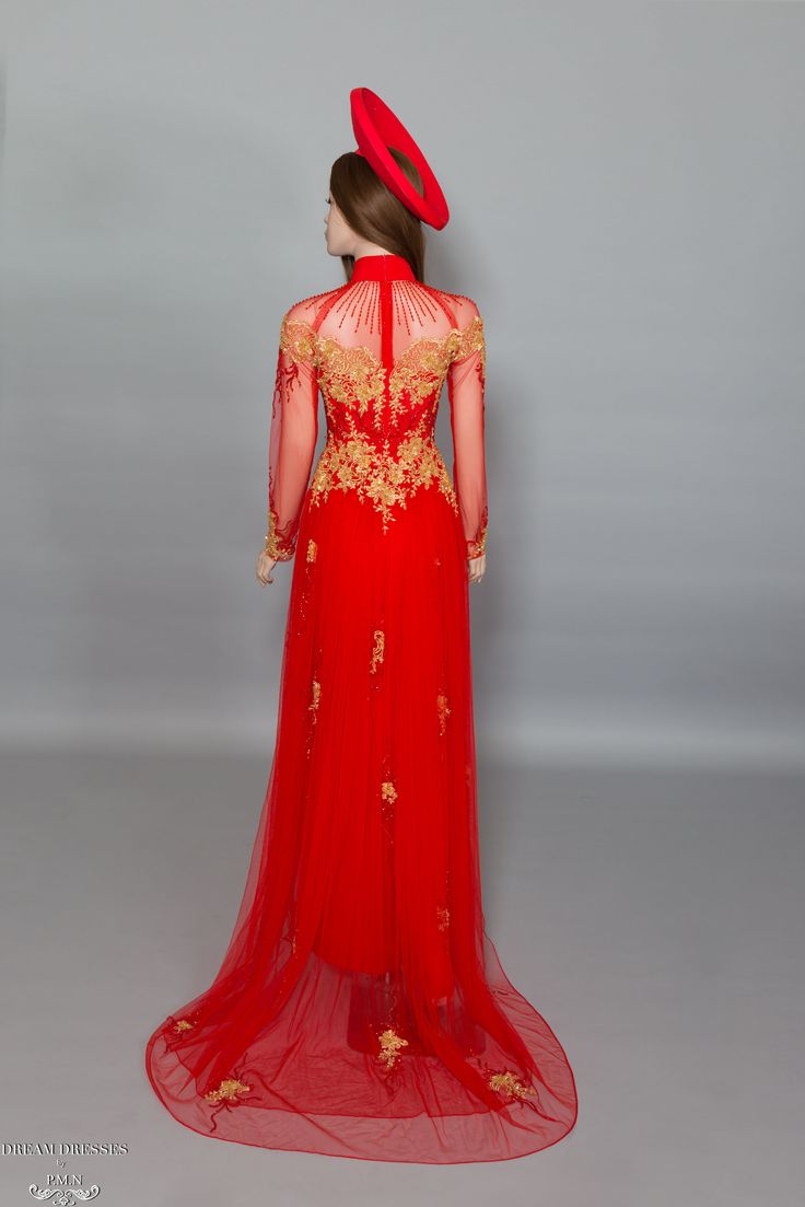 a woman in a red dress and hat is looking at the back of her gown