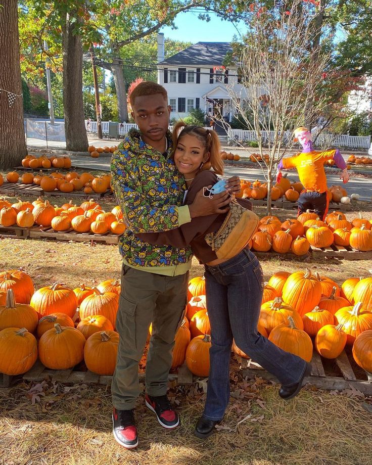 a man and woman standing in front of pumpkins