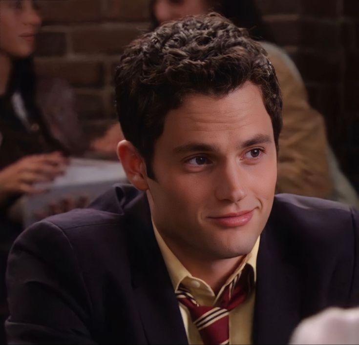 a man in a suit and tie sitting at a table with other people around him