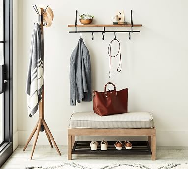 a white room with a bench, coat rack and shoes on the shelf next to it