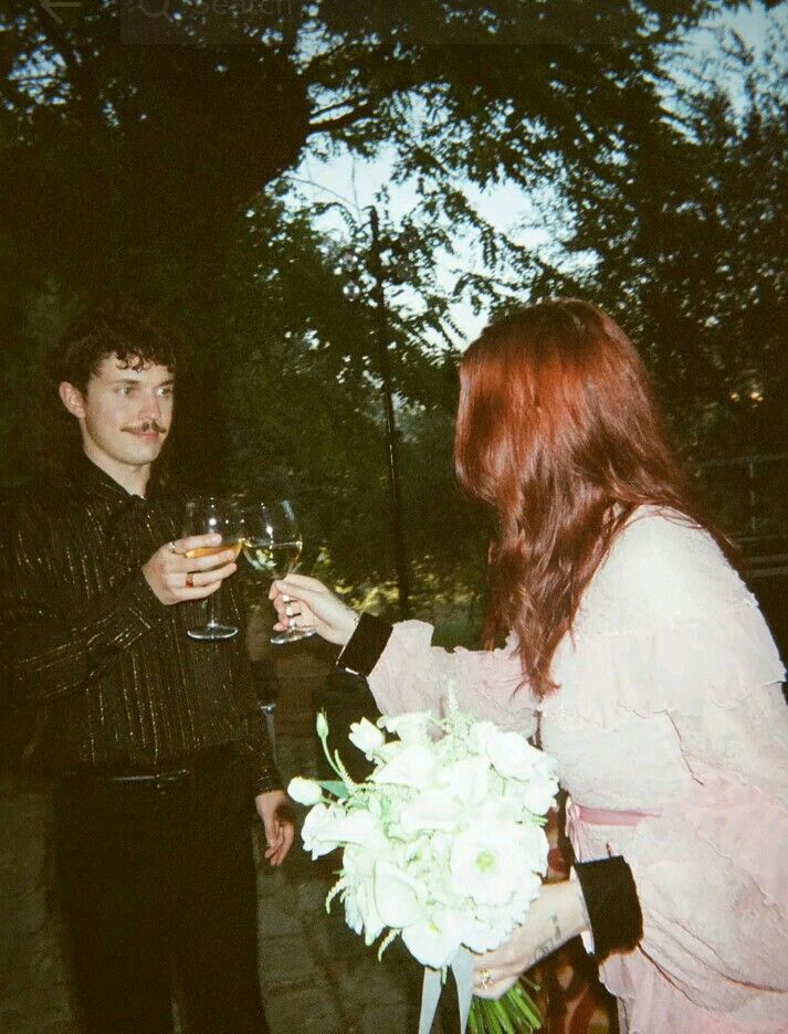 two people standing next to each other holding wine glasses