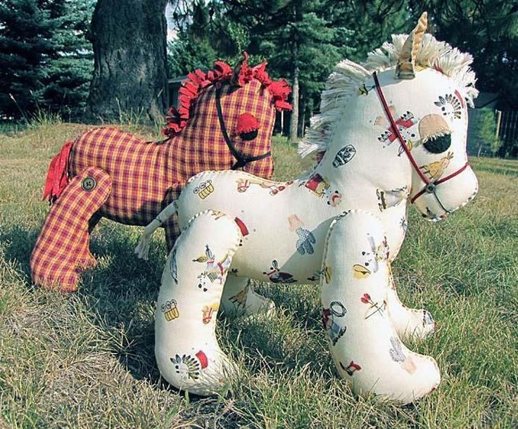 two large stuffed animals sitting on top of a lush green field covered in grass and trees