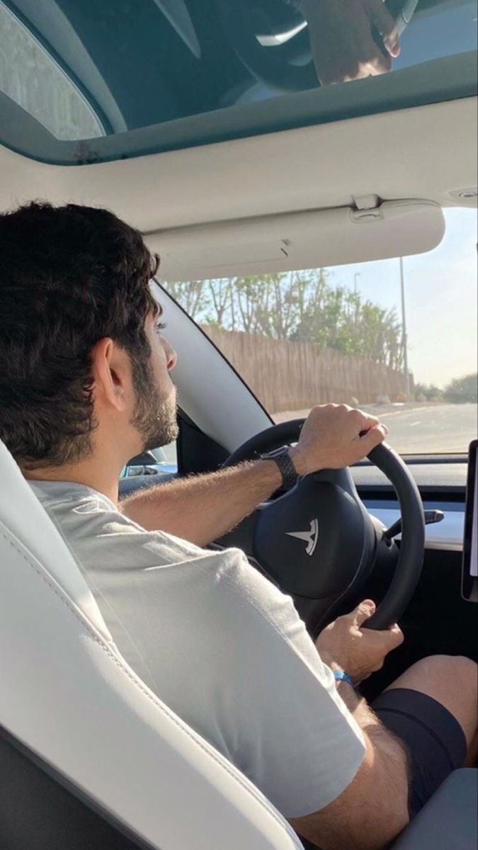 a man sitting in the driver's seat of a car using a laptop computer