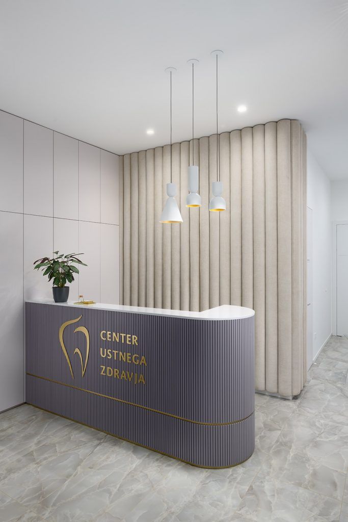 the front desk of a dental office with hanging lights above it and a potted plant on the counter